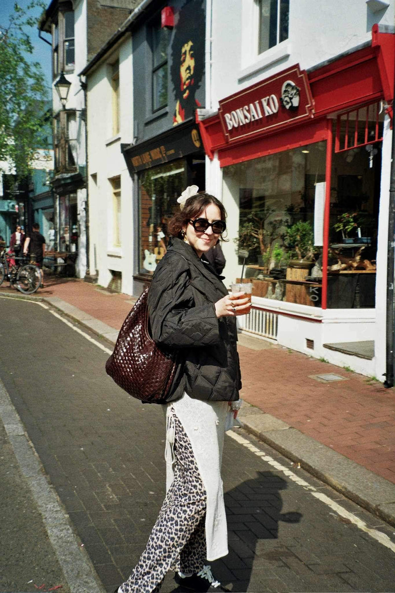 Main de femme avec ongles noirs coupant du beurre avec un couteau vintage sur un plat en métal argenté